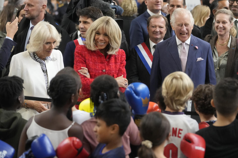 Britain's Queen Camilla , left, French President Emmanuel Macron's wife Brigitte Macron, second left, and Britain' s King Charles III talk to children exercising boxing during a visit to a gymnasium, Thursday, Sept. 21, 2023 in Saint-Denis, outside Paris. (AP Photo/Thibault Camus)