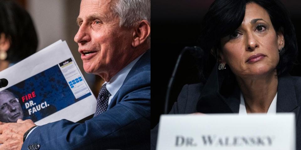 dr fauci holds up a sign that says 'fire fauci' and dr walensky looks stern