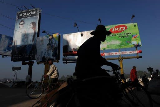 A man rides his trishaw past billboards along the Pathein river front in Pathein, west of Yangon. As sanctions in Myanmar loosen, a rush of firms are looking to tap a potential 62 million consumers and a young workforce in an economy that the IMF says is set to grow 5.5 percent this year