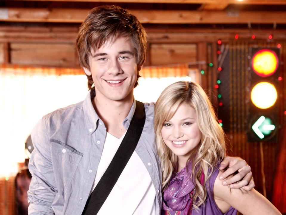 Olivia Holt and Luke Benward with their arms around each other.