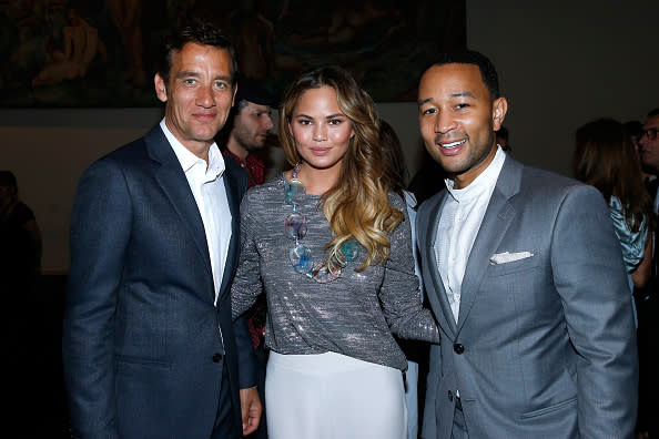 <p>Teigen, who wore wide leg pants from Giorgio Armani’s 2015 Resort Collection, was sandwhiched between the two suited men. </p>