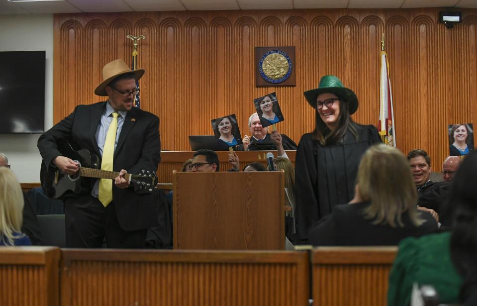 Attorney Jeffrey Battista (left) and Judge Nicole Menz (right) perform a comedy routine as fellow judges wave photos of Leatha Mullins before her swearing in during the Investiture Ceremony for Mullins at the St. Lucie County Courthouse on Friday, Feb.24, 2023, in Fort Pierce.