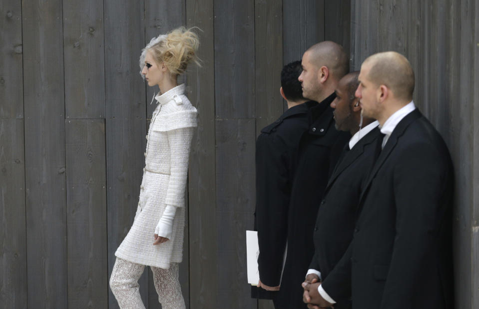 Security officers watch a model wearing a creation by German fashion designer Karl Lagerfeld for Chanel's Spring-Summer 2013 Haute Couture fashion collection, presented in Paris, Tuesday, Jan.22, 2013. (AP Photo/Christophe Ena)