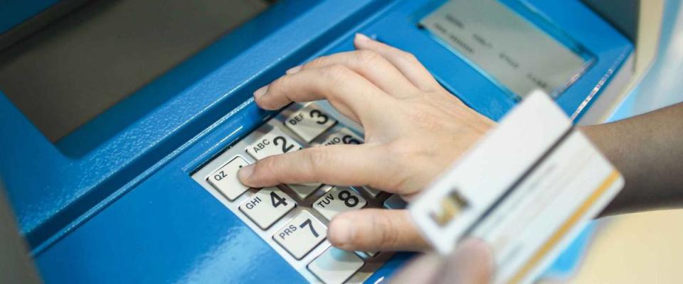Woman pushing password on button of ATM machine for cash deposit