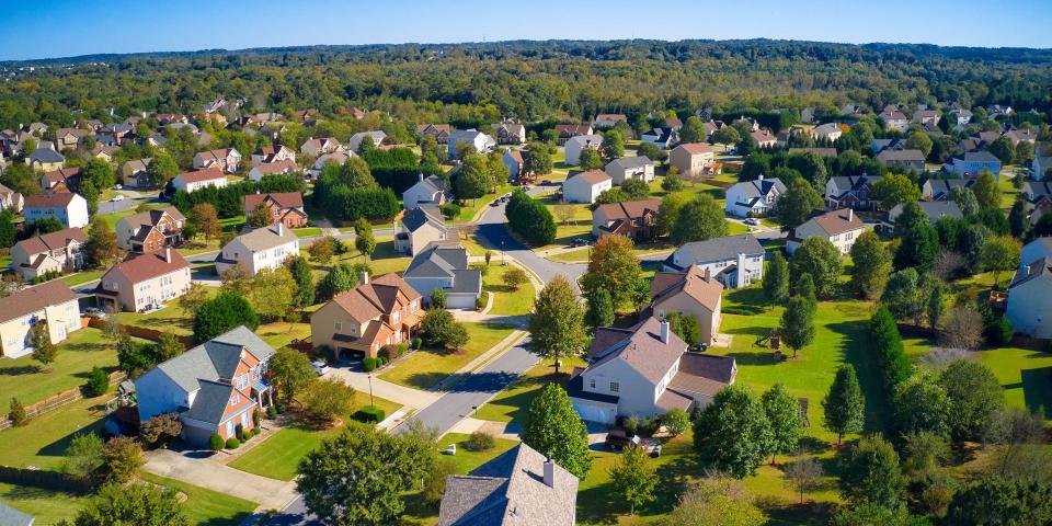 Shot using a drone during the golden hour shows an upscale suburbs with gold course, lake, houses and roof tops in Atlanta.