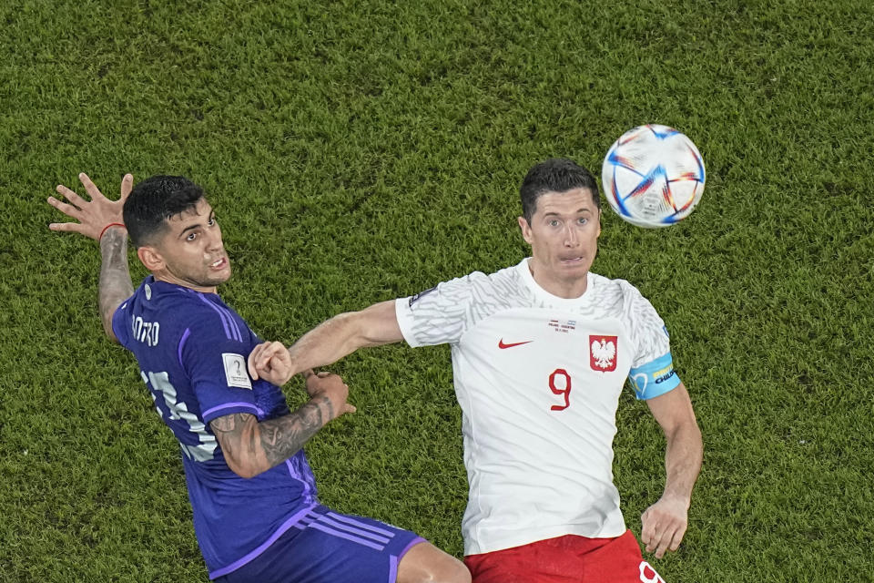 Argentina's Cristian Romero, left, challenges for the ball with Poland's Robert Lewandowski during the World Cup group C soccer match between Poland and Argentina at the Stadium 974 in Doha, Qatar, Wednesday, Nov. 30, 2022. (AP Photo/Pavel Golovkin)