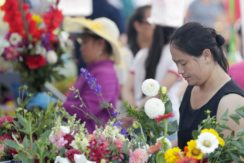 Ia Lee arranges flowers at her booth at the Saturday Farmers Market in downtown Green Bay. The market opens for its 108th season on May 25.