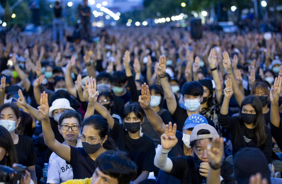 Pro-democracy activities raise a three-fingers, symbol of resistance salute during a protest at Democracy Monument in Bangkok, Thailand, Sunday, Aug, 16, 2020. Protesters have stepped up pressure on the government demanding to dissolve the parliament, hold new elections, amend the constitution and end intimidation of the government's opponents. (AP Photo/Gemunu Amarasinghe)