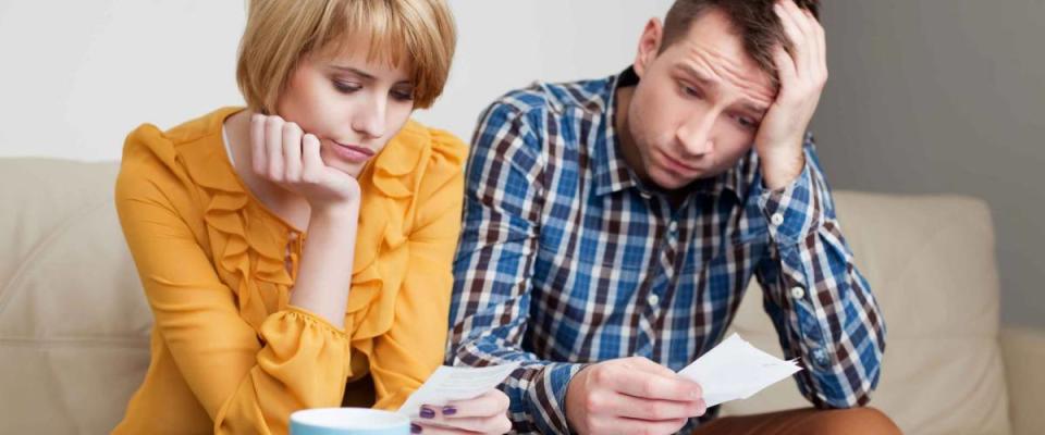 Sad, depressed young couple paying bills.