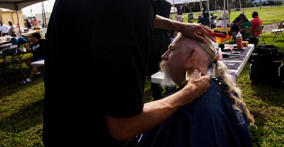 Angel Mijangos, a student at Itech in Immokalee trims Mark CabralÕs hair at Collier County Hunger and Homeless CoalitionÕs annual "point in time" homeless count at Gulf Gate Plaza in Naples on Friday, Jan. 26, 2024. Cabral has been homeless in Naples eight years, he said. Vendors were set up at the event to help the homeless which included, food, hygiene kits, clothes and other help.