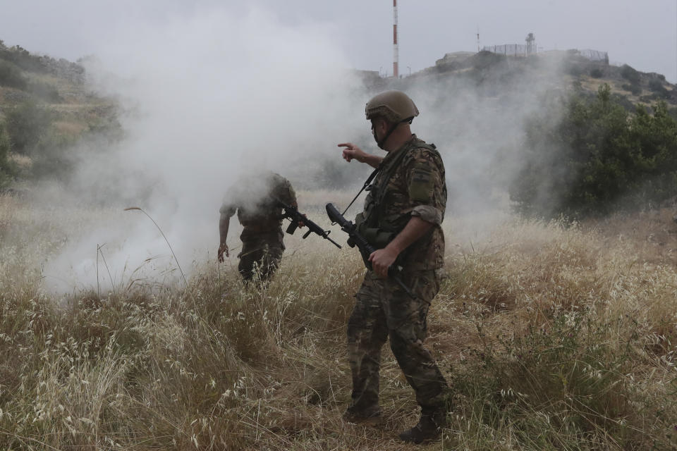 Lebanese soldiers covered in smoke after Israeli soldiers fired tear gas, at the Lebanese border village of Kfar Chouba, south Lebanon, Friday, June 9, 2023. Israeli soldiers fired tear gas to disperse scores of protesters who pelted the troops with stones along the border with Lebanon Friday, leaving some Lebanese demonstrators and troops suffering breathing problems. (AP Photo/Mohammad Zaatari)