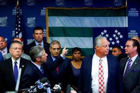 NYPD Police Benevolent Association President Lynch points to the NYPD flag which is hanging upside down as a protest at a news conference in New York