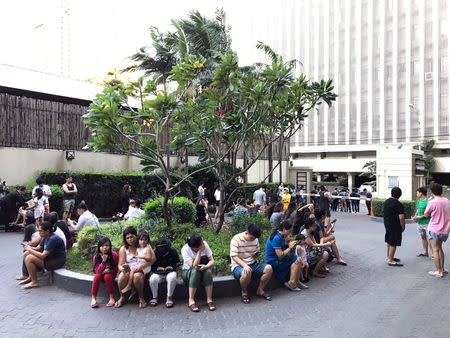 Residents sit outside after being evacuated from the condominium building after an earthquake in Makati City, Philippines, April 22, 2019. REUTERS/Martin Petty