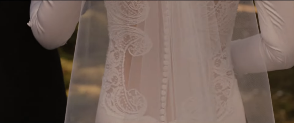 Close-up of a person's midsection in an elegant, detailed lace dress, likely at a formal event