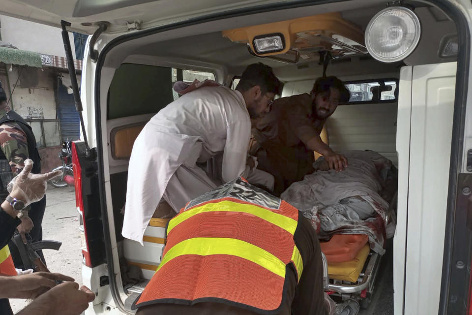 Volunteers and a rescue worker load a victim in an ambulance at the site of a bomb blast in Dera Ismail Khan, Pakistan, Friday, Nov. 3, 2023. A bomb planted in a parked motorcycle exploded near a police vehicle in northwest Pakistan, killing multiple people and wounding more Friday, police said. (AP Photo/Irfan Mughal)