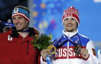 Austria's Benjamin Karl, the bronze medalist in the men's snowboard parallel slalom, left, smiles while standing next to gold medalist Vic Wild of Russia, who also won the gold medal in the men's snowboard parallel giant slalom, during their medals ceremony at the 2014 Winter Olympics, Saturday, Feb. 22, 2014, in Sochi, Russia. (AP Photo/David Goldman)