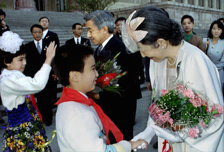 FILE PHOTO: Smiling Japanese Empress Michiko shakes the hand of a Chinese boy as she and Emperor Akihito receive flower bouquets from young wellwishers during the welcoming ceremony for the Imperial couple's historic visit to China at Beijing's Great Hall of the People, October 23, 1992. Pool via Reuters/File Photo