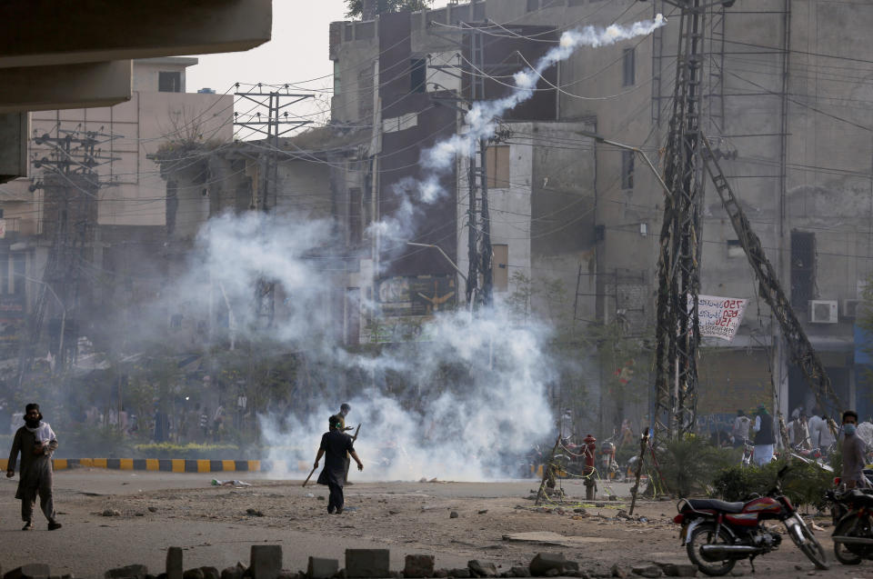 An angry supporter of Tehreek-e-Labiak Pakistan, a radical Islamist political party, hurls back a tear gas shell fired by police to disperse them, at a protest against the arrest of their leader Saad Rizvi, in Lahore, Pakistan, Monday, April 12, 2021. Pakistan police arrested Rizvi a day after he threatened the government with protests if it did not expel France's ambassador over depictions of Islam's Prophet Muhammad. (AP Photo/K.M. Chaudary)