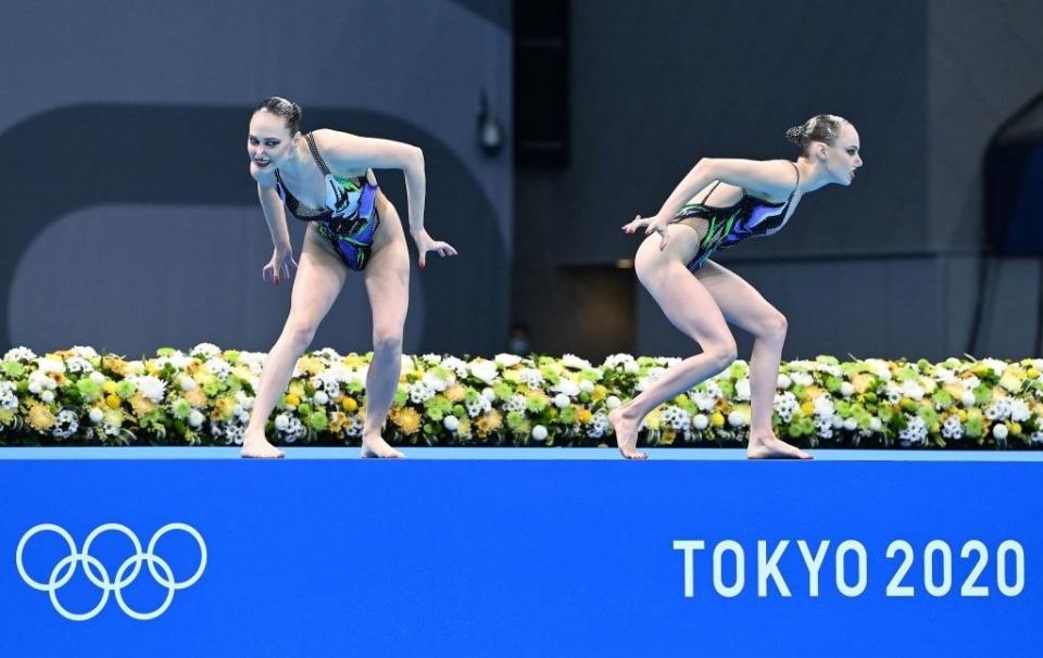 Two swimmers crouch away from each other