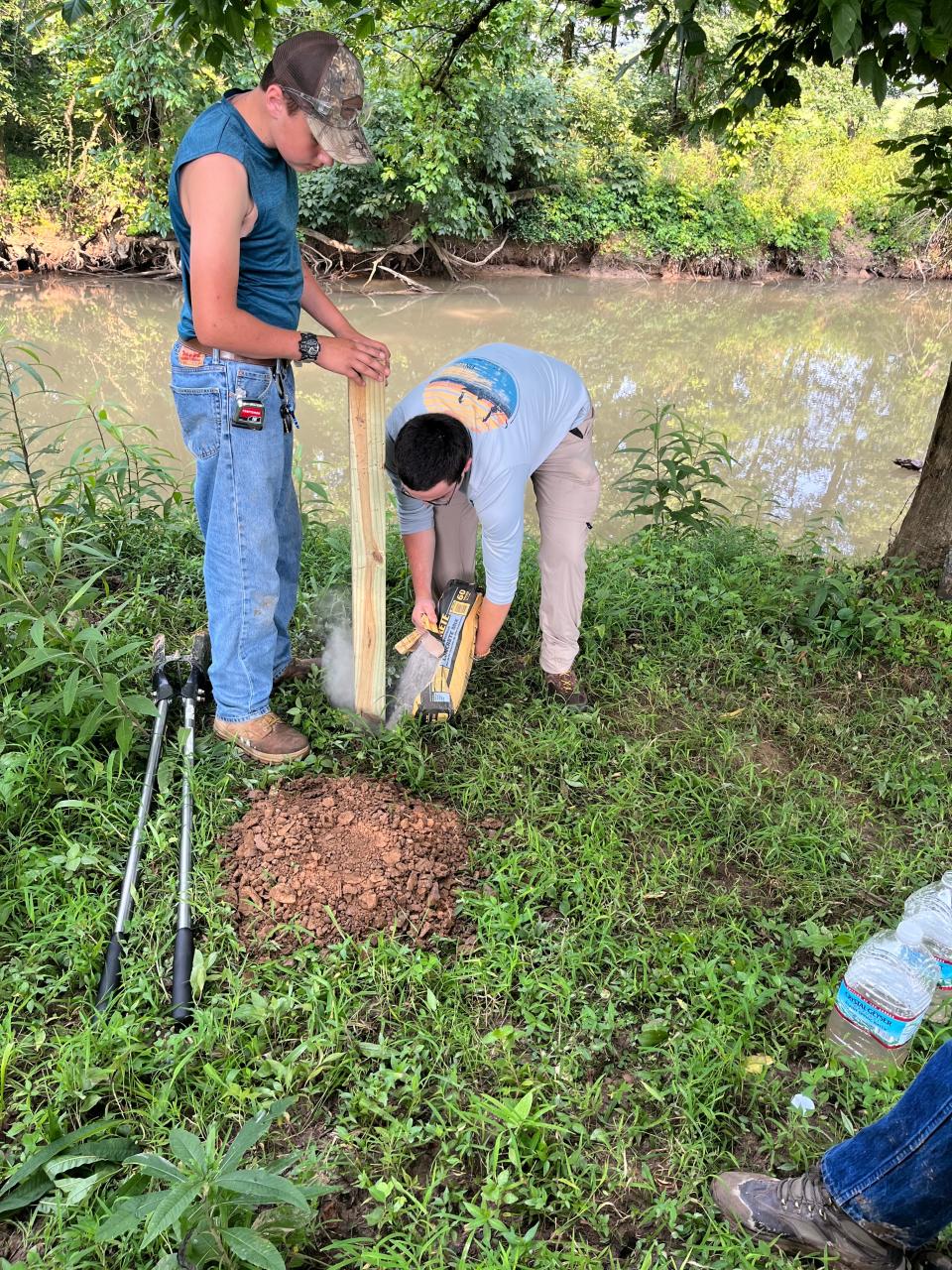 Henry Jordan (left) and Andrew Phillips completed their Eagle Scout projects by mapping Beaver Creek and posting mileage signs along the bank to help first responders with any emergency. Pouring cement for the signposts was an important part of the project. Aug 2022-Oct 2023