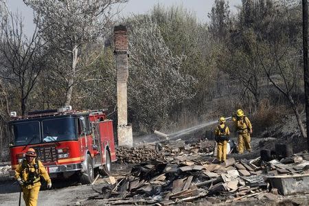 Firefighters hose down a burnt structure at the so-called Blue Cut Fire in the San Bernardino National Forest in San Bernardino County, California, U.S. August 18, 2016. REUTERS/Gene Blevins