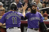 Colorado Rockies' Mike Moustakas gets a high-five from Charlie Blackmon after scoring the Rockies first run during the second inning of a baseball game against the Arizona Diamondbacks, Thursday, June 1, 2023, in Phoenix. (AP Photo/Darryl Webb)