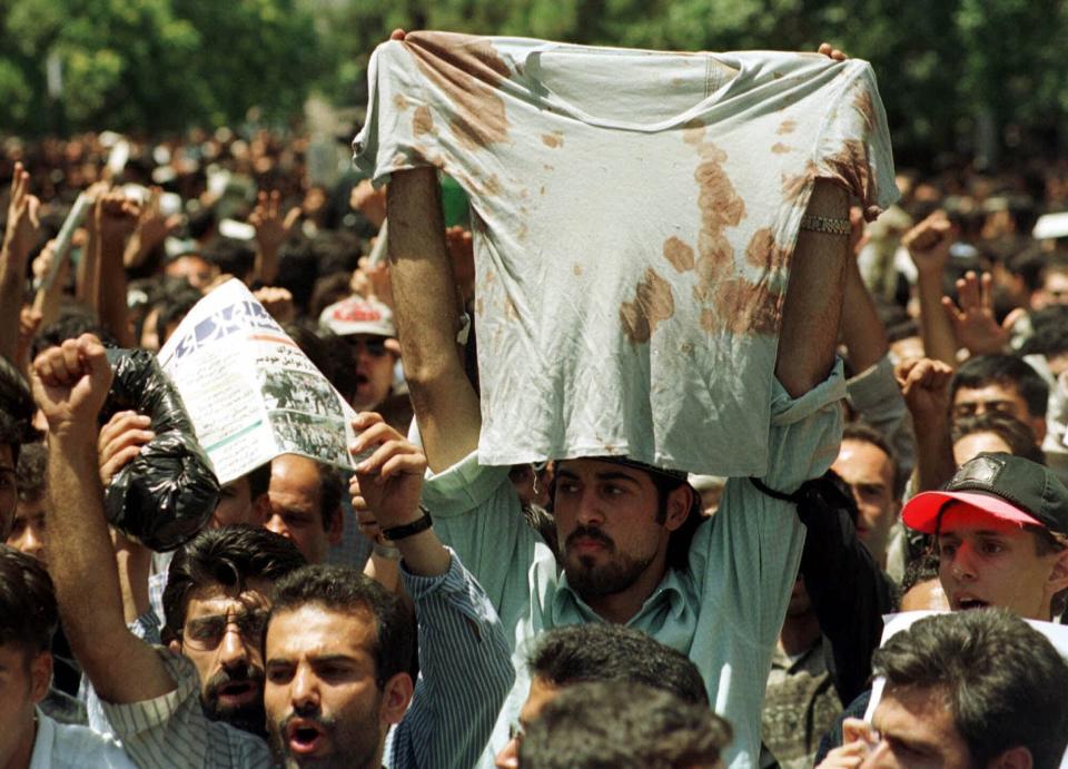 FILE - In this July 12, 1999 file photo, an unidentified student at a rally in Tehran, Iran, holds up the bloody t-shirt of a friend who was injured sometime in the last few days during clashes between police and student demonstrators. The demonstrations that erupted after Iran admitted to accidentally shooting down a Ukrainian jetliner early Wednesday, Jan. 8, 2020, during a tense standoff with the United States, are the latest of several waves of protest going back to the 1979 Islamic Revolution — all of which have been violently suppressed. (AP Photo/Kamran Jebreili, File)