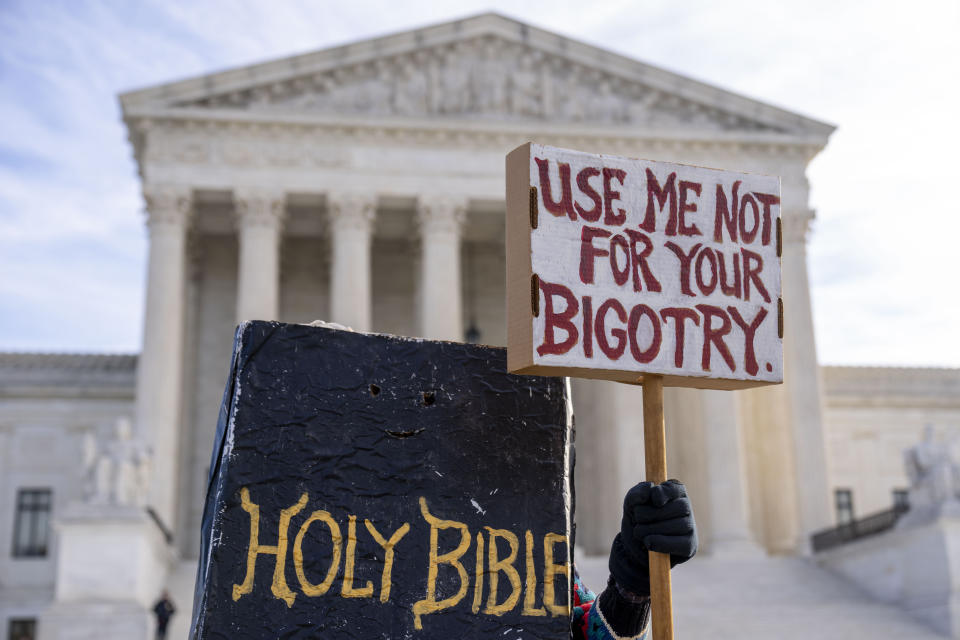 A person dressed as a bible holds a sign that reads "Use Me Not For Your Bigotry" outside the Supreme Court in Washington, Monday, Dec. 5, 2022. The Supreme Court is hearing the case of a Christian graphic artist who objects to designing wedding websites for gay couples, that's the latest clash of religion and gay rights to land at the highest court. (AP Photo/Andrew Harnik)