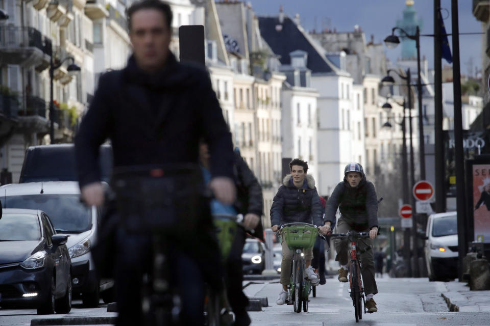 FILE - People ride bicycles through Paris, Friday, Dec. 20, 2019. Over the quarter century since Paris was regarded as bicycle-unfriendly, the city has taken striking measures to get people on wheels, even subsidizing one third of the cost for people to buy 85,000 electric bikes or cargo bikes from 2009 to 2022. (AP Photo/Christophe Ena, File)