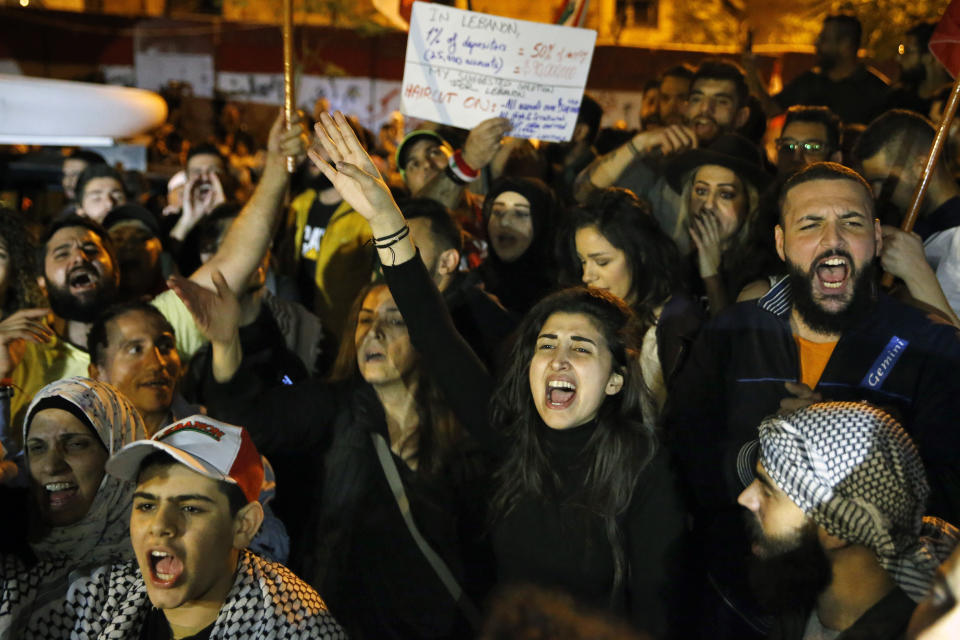 Anti-government protesters chant slogans, during ongoing protests against the Lebanese government, in front of the Central Bank, in Beirut, Lebanon, Thursday, Nov. 28, 2019. Lebanon paid back a Eurobond worth $1.5 billion that was scheduled to mature Thursday, a Finance Ministry official said, pacifying concerns of a first-ever default on its debt amid the worst financial crisis in three decades. (AP Photo/Bilal Hussein)