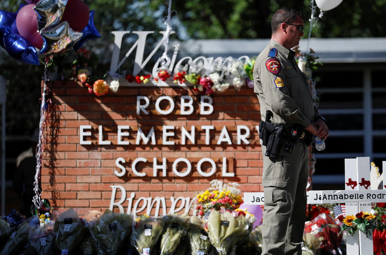 A Texas Department of Public Safety officer stands in front of crosses with the names of victims of a school shooting, at a memorial outside Robb Elementary school, two days after a gunman killed nineteen children and two adults, in Uvalde, Texas, U.S. May 26, 2022. REUTERS/Marco Bello