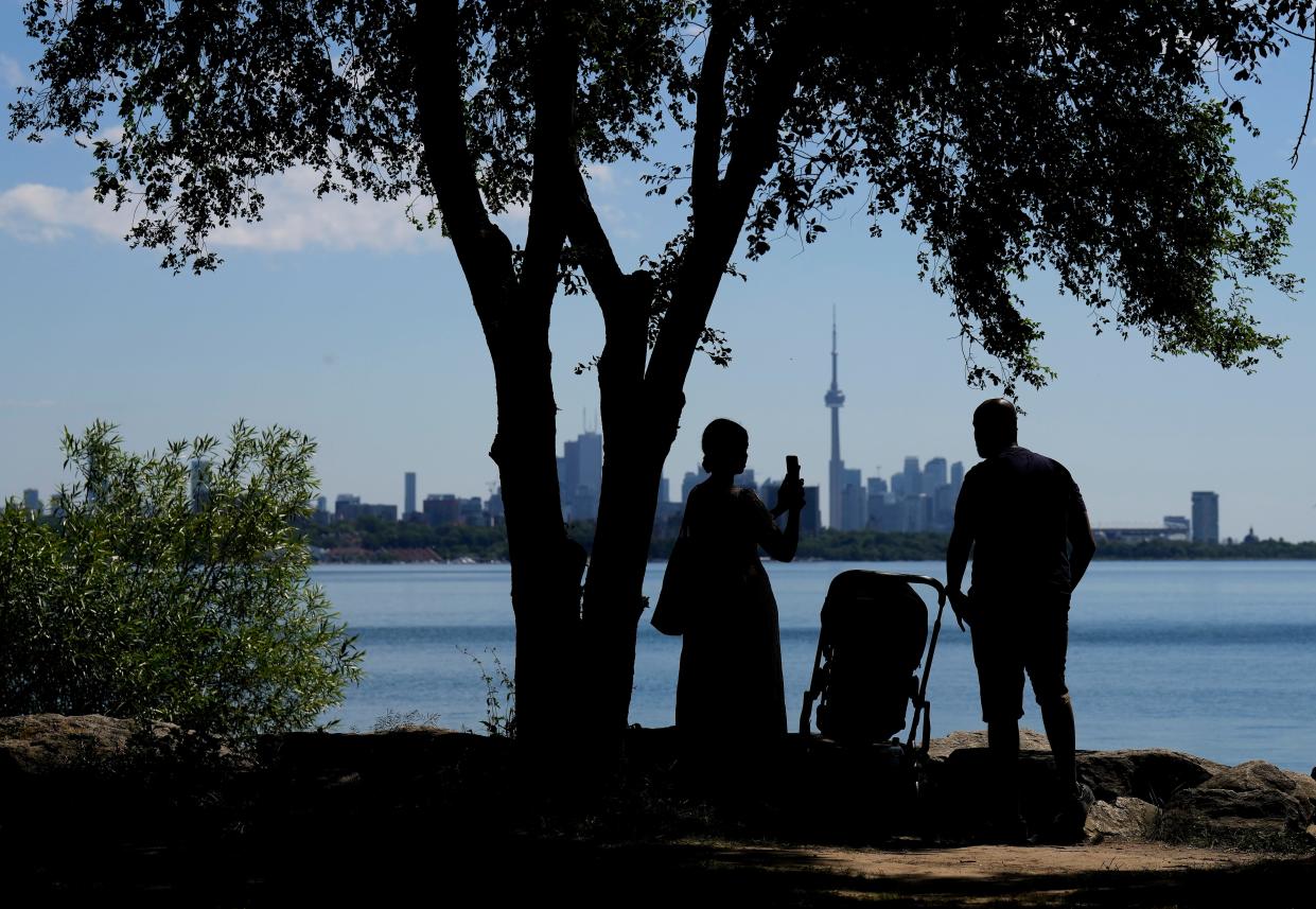 A family take pictures in the shade on a hot day in Toronto on Thursday.