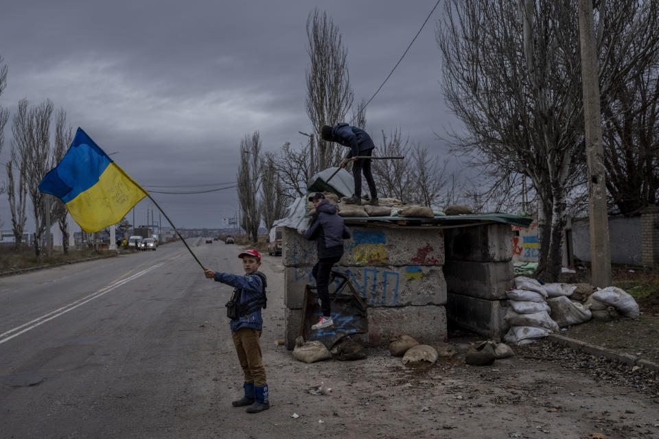 FILE - Ukrainian children play at an abandoned checkpoint in Kherson, southern Ukraine, Wednesday, Nov. 23, 2022. Quantifying the toll of Russia’s war in Ukraine remains an elusive goal a year into the conflict. Estimates of the casualties, refugees and economic fallout from the war produce an complete picture of the deaths and suffering. Precise figures may never emerge for some of the categories international organizations are attempting to track. (AP Photo/Bernat Armangue, FIle)