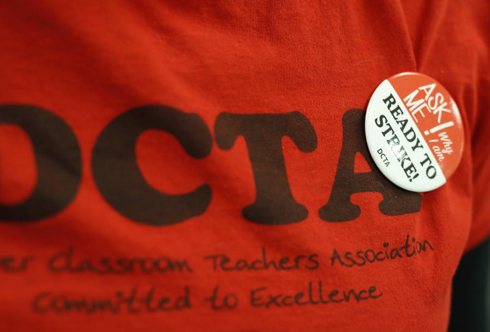 FILE - In this Thursday, Jan. 17, 2019, file photograph, a teacher wears a button on a union shirt in the Denver Classroom Teachers Association, the union's headquarters in south Denver. Teachers voted Tuesday, Jan. 22, 2019, to authorize a strike, which would be the first called in 25 years in the state's largest school district. (AP Photo/David Zalubowski, File)
