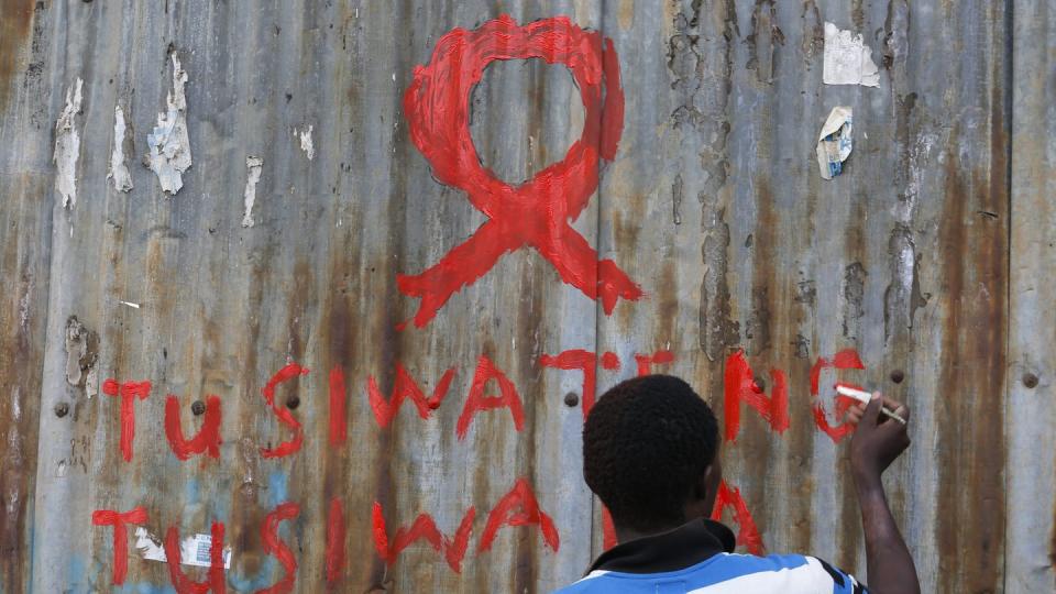 Ein junger Mann malt eine rote Aids-Schleife auf eine Wand im Kibera-Slum in Nairobi. Foto: Dai Kurokawa/Illustration