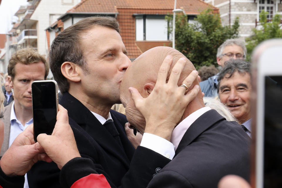 French President Emmanuel Macron, left, kisses the head of a wellwisher after voting in the European elections in Le Touquet, northern France, Sunday May 26, 2019. France is looking at an epic battle between pro-EU centrist President Emmanuel Macron and anti-immigration, far-right flagbearer Marine Le Pen in the European Parliament vote, a duel over Europe's basic values. (Ludovic Marin/Pool via AP)