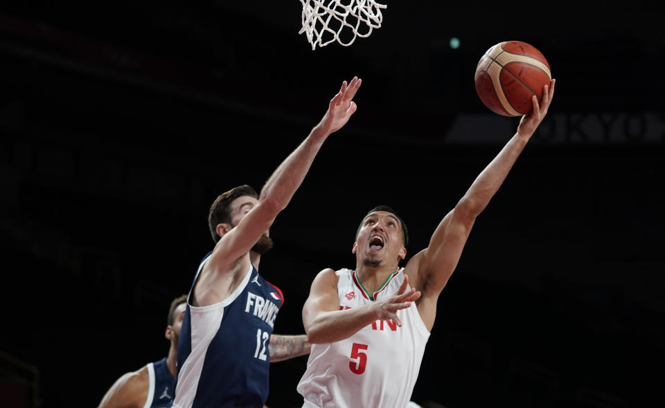 Iran's Pujan Jalalpoor (5), right, shoots ahead of France's Nando de Colo (12) during men's basketball preliminary round game at the 2020 Summer Olympics, Saturday, July 31, 2021, in Saitama, Japan. (AP Photo/Charlie Neibergall)