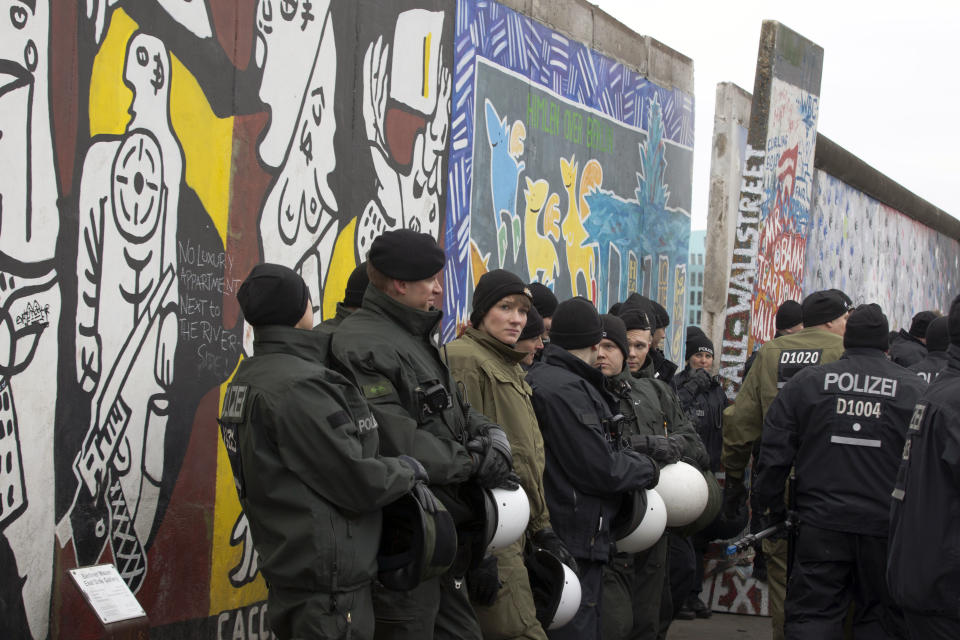 German police officers protect a part of the former Berlin Wall in Berlin, Germany, Friday, March 1, 2013. Construction crews stopped work Friday on removing a small section from one of the few remaining stretches of the Berlin Wall to make way for a condo project after hundreds of protesters blocked their path. (AP Photo/Markus Schreiber)