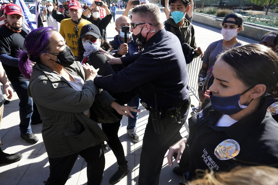 Police shove two counterdemonstrators during a pro-Trump rally outside of police headquarters Wednesday in Los Angeles. (AP Photo/Marcio Jose Sanchez)