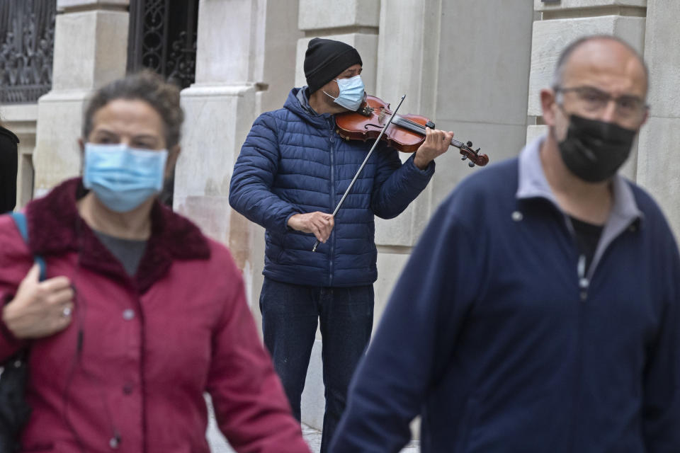 A street musician plays for passers-by in Madrid, Spain, Sunday, Nov. 15, 2020. Spain continues with new measures against the COVID-19 while suffering a second strong pandemic crisis by Coronavirus. (AP Photo/Paul White)