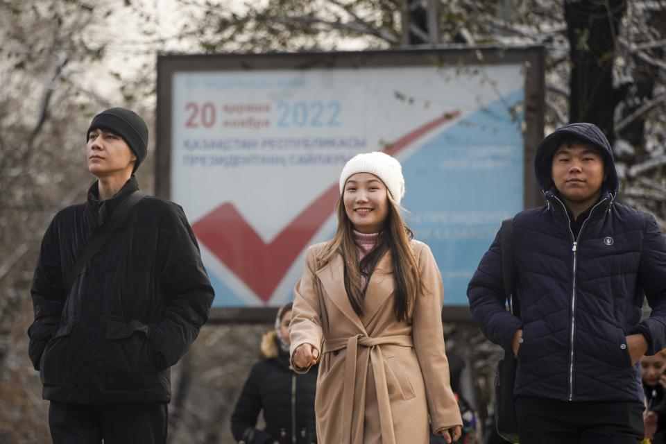 Kazakh youth walk down a street with an election poster in the background in Almaty, Kazakhstan, Thursday, Nov. 17, 2022. Kazakhstan's president, who faced a bloody outburst of unrest early this year and then moved to marginalize some of the Central Asian country's longtime powerful figures, appears certain to win a new term against little-known challengers in a snap election on Sunday. (Vladimir Tretyakov/NUR.KZ via AP)