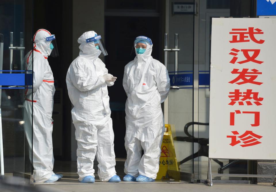 FILE - In this Jan. 28, 2020 file photo, medical staff in protective outfits wait at the entrance of a clinic for fever patients and patients from Wuhan in Fuyang in central China's Anhui Province.  As China institutes the largest quarantine in human history, locking down more than 50 million people in the center of the country, those who have recently been to Wuhan are being tracked, monitored, turned away from hotels and shoved into isolation at their homes and in makeshift quarantine facilities.  (Chinatopix via AP. File)