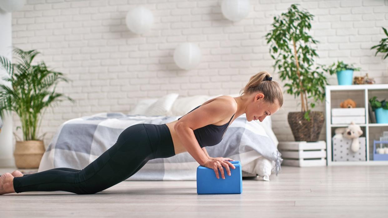  Woman performing a push-up on yoga blocks during at home workout. 