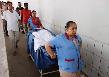 Staff carry the body of a girl who died of acute encephalitis syndrome to an ambulance at a hospital in Muzaffarpur