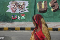 FILE - In this Feb. 18, 2020, file photo, a woman looks at a wall painted with portraits of U.S. President Donald Trump and Indian Prime Minister Narendra Modi ahead of Trump's visit, in Ahmedabad, India. To welcome Trump, who last year likened Modi to Elvis Presley for his crowd-pulling power at a rally in Houston, the Gujarat government has spent almost $14 million on ads blanketing the city that show the two leaders holding up their hands, flanked by the Indian and U.S. flags. It also scrambled to build a wall to hide a slum from the road Trump and first lady Melania Trump will travel, caught stray dogs, planted exotic trees and is rushing to finish a cricket stadium in time for Trump’s arrival. (AP Photo/Ajit Solanki, File)