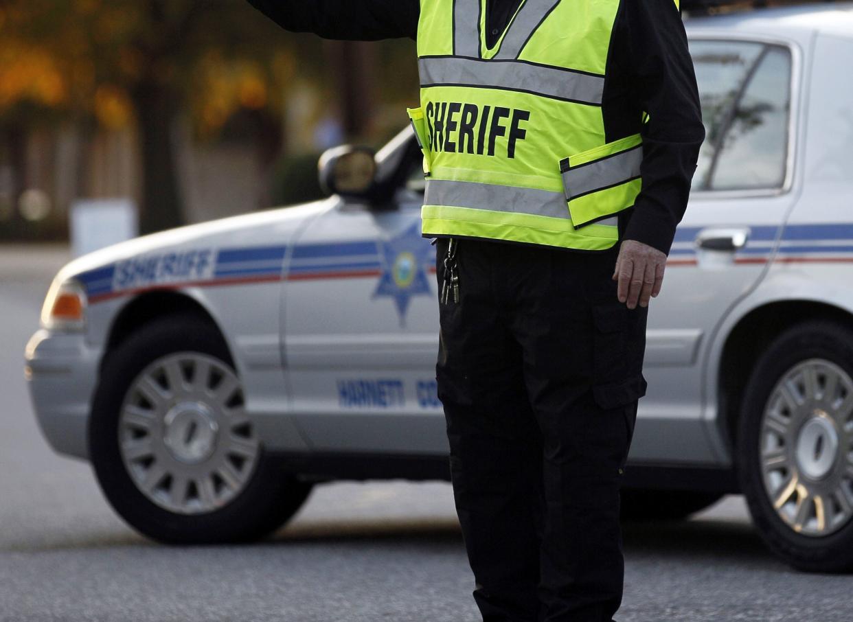 FILE - A member of the Harnett County Sheriff's office directs traffic at a roadblock at Campbell University in Buies Creek, N.C., Wednesday, Nov. 9, 2011. 