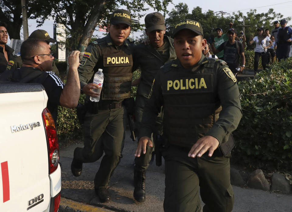 A Venezuelan National Guard, center, deserts his post as Colombian Police escort him after he managed to cross the Simon Bolivar International Bridge where his fellow guardsmen are blocking the entry of U.S.-supplied humanitarian aid, in La Parada, Colombia, Monday, Feb. 25, 2019, on the border with Venezuela. The delivery of humanitarian aid to the economically devastated nation has faltered amid strong resistance from security forces who remain loyal to Venezuelan President Nicolas Maduro. (AP Photo/Fernando Vergara)