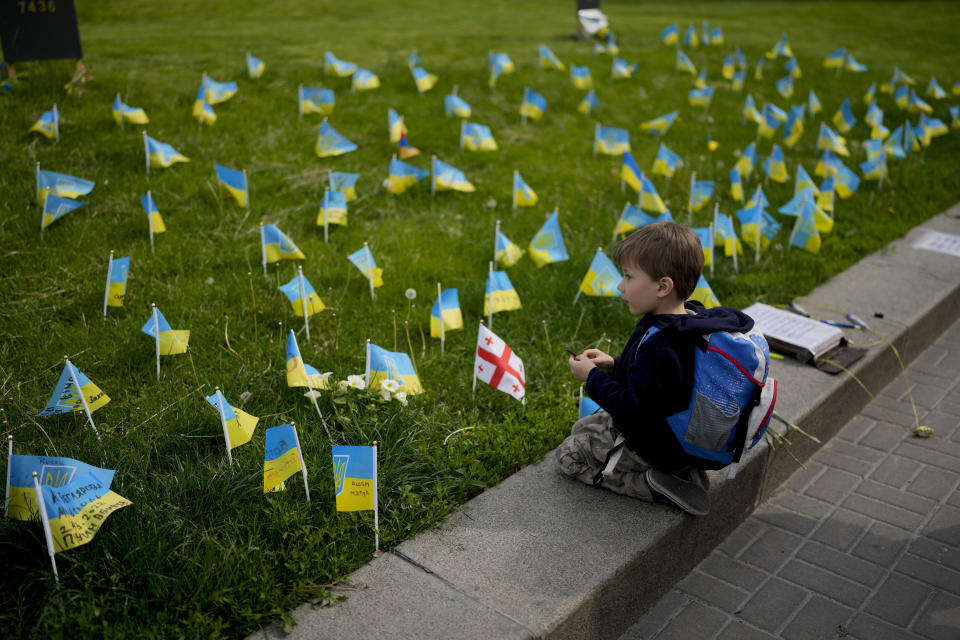 A boy watches flags honoring soldiers killed fighting Russian troops in downtown Kyiv, Ukraine, Monday, May 23, 2022. (AP Photo/Natacha Pisarenko)