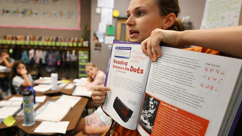 First-year teacher Margaret “Maggie” Johnston holds up a workbook as she works with her students at Crescent Elementary School in Sandy on Tuesday, Sept. 19, 2023.