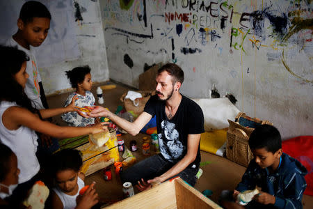 Jorge (C), 31, who is among members of lesbian, gay, bisexual and transgender (LGBT) community, that have been invited to live in a building that the roofless movement has occupied, teaches children to draw, in downtown Sao Paulo, Brazil, November 15, 2016. REUTERS/Nacho Doce